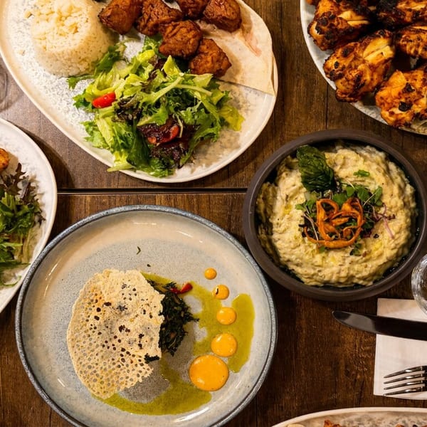 Overhead view of a wooden table laden with various Middle Eastern dishes, including grilled chicken, rice, and salads.